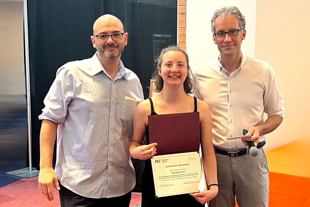 Kaitlyn Yanna in the center holding an award certificte with Matteo Buccito the left and Jacopo Buongiorno to the right, in a row, MIT